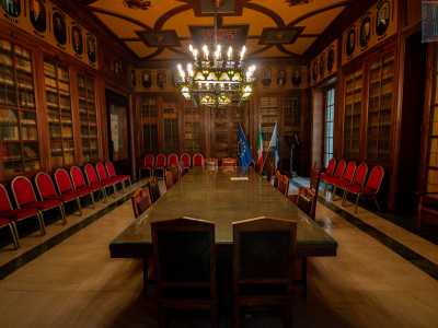 Uscendo, accediamo subito  all�adiacente Sala della Giunta, un tempo biblioteca, come si nota dalle teche colme di libri che ricoprono i muri. Al centro, un lungo tavolo in legno massello...